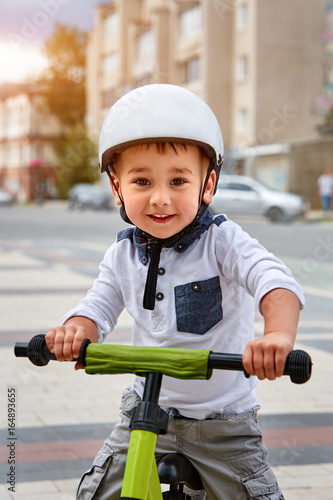 Happy boy in white helmet ride his first bike