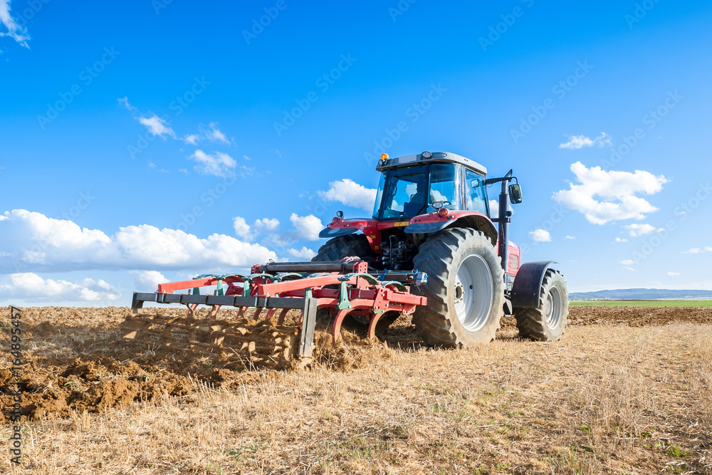 Obraz premium agricultural tractor in the foreground with blue sky background.