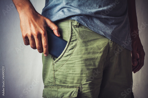close-up of a hand about to taking a smart phone from a pant's pocket