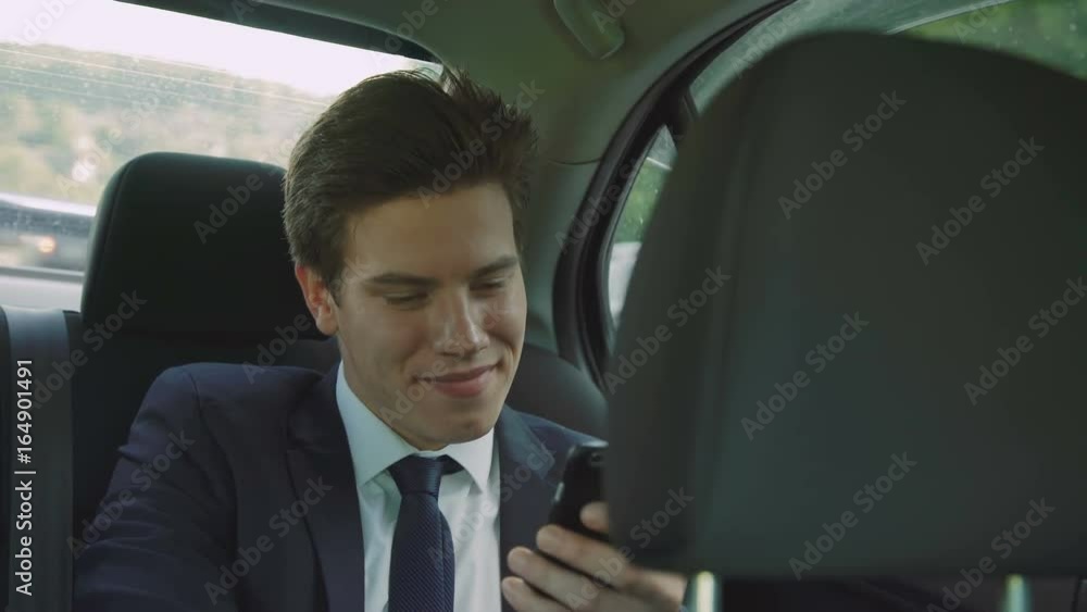 Young businessman going in the car and using the smartphone 4K