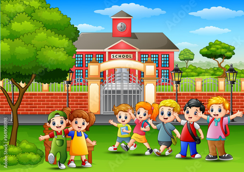 Happy school children standing in front of school building