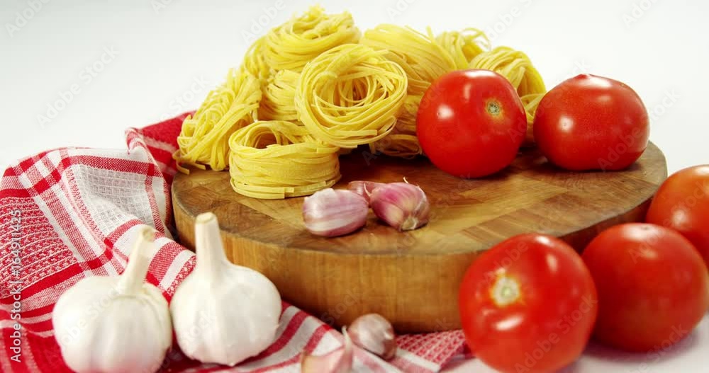 Tomatoes and raw pasta on chopping board Tomatoes and raw pasta on chopping board
