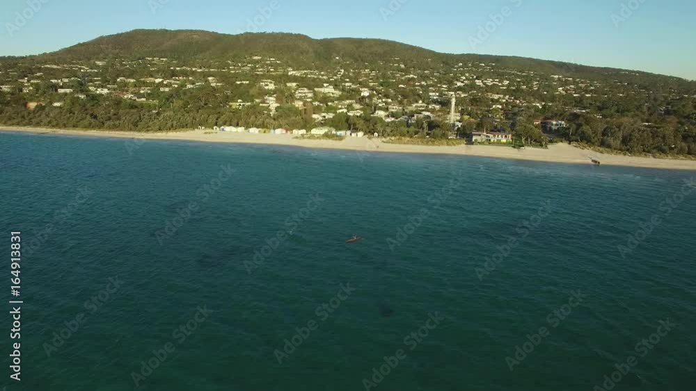 Forward flight over Port Phillip Bay waters passing kayaker towards Mornington Peninsula coastline at sunset Forward flight over Port Phillip Bay waters passing kayaker towards Mornington Peninsula coastline at sunset