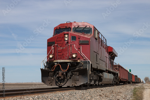 Big Red Locomotive Leading Freight Train on Prairie