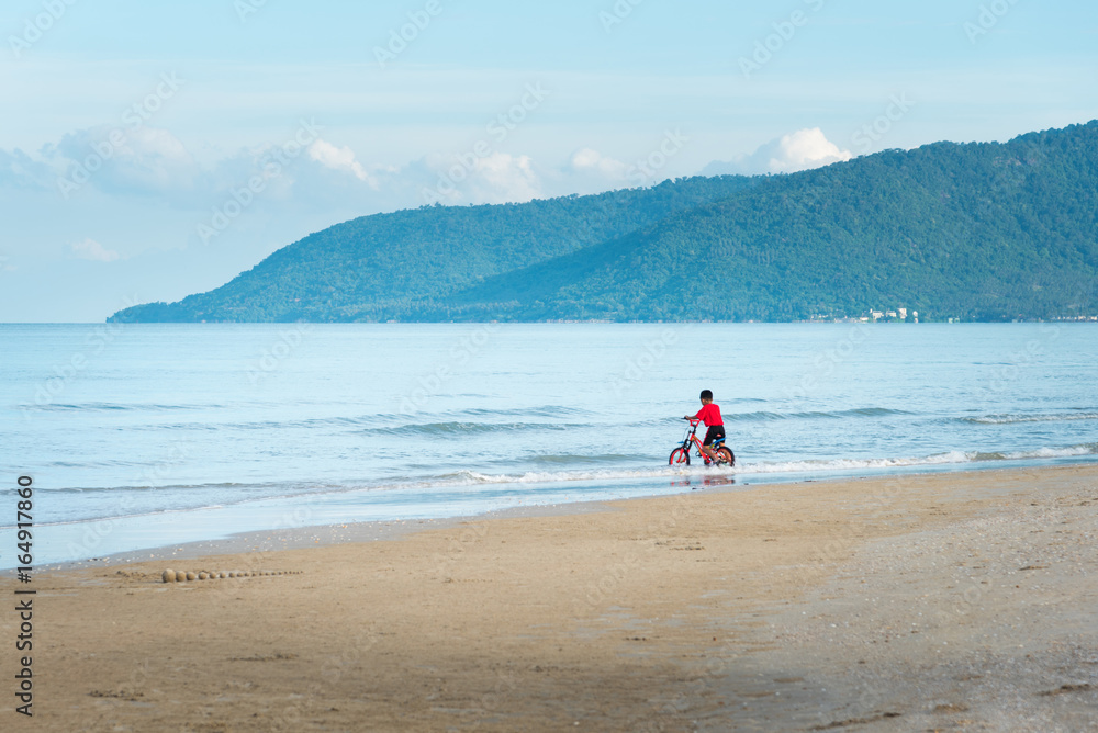  kid boy driving bicycle in the beach