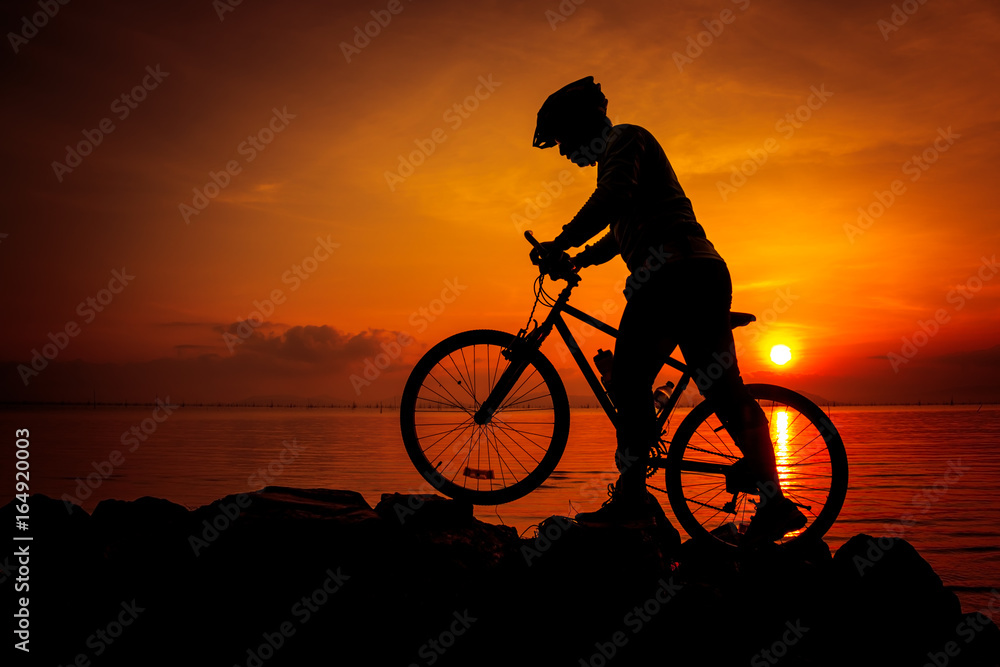 Obraz premium Silhouette of bicyclist enjoying the view at seaside. Outdoors.