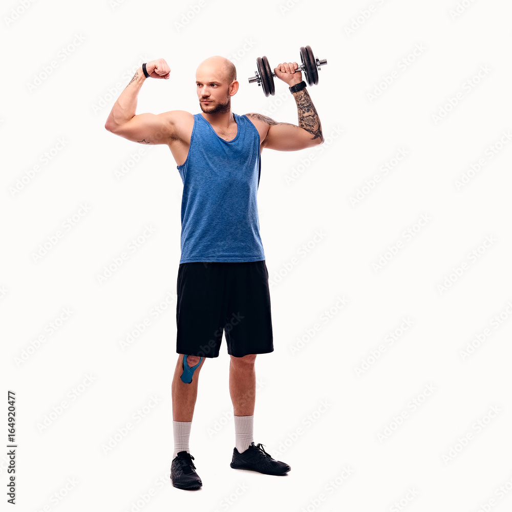 Shaved head male holds dumbbell. Shaved head male holds dumbbell.