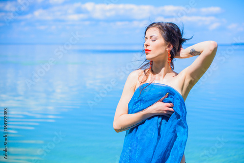 Tale gorgeous mermaid girl with dark hair in blue lagoon . Sexy and thin figure, red lips and pale skin. Inspire woman in blue cloth bathed in water and seduces mans 