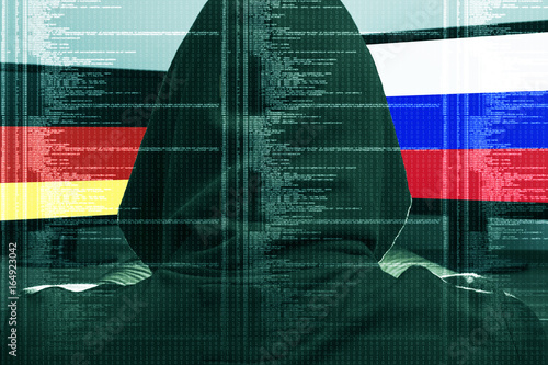 Hacker working on a cyber attack on Germany and Russia. Concept of hacking into the computer. Ger and Rus flag on the screen. German and Russian flag on the screen.