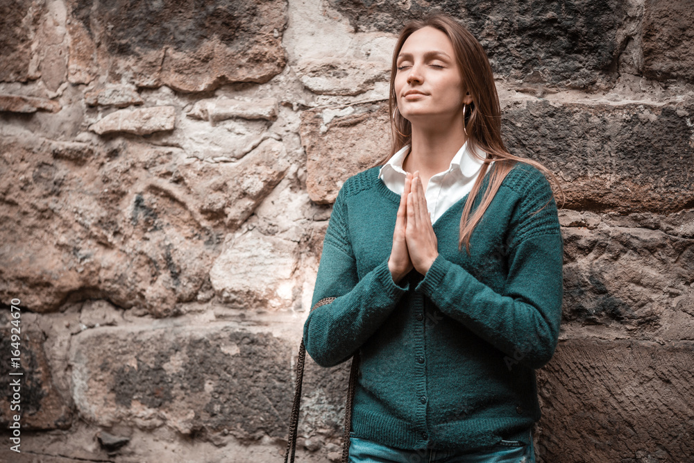 Serene woman in ancient town, with praying hands, history Serene woman in ancient town, with praying hands, history