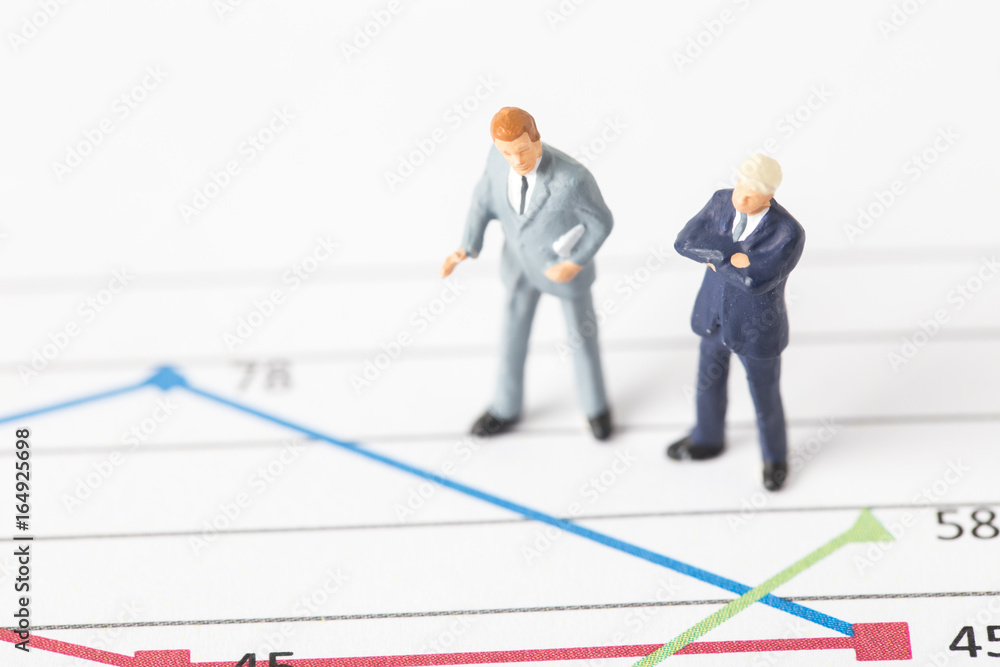 Miniature model of businessman thinking with project for presenting investment concept on graph. Miniature model of businessman thinking with project for presenting investment concept on graph.