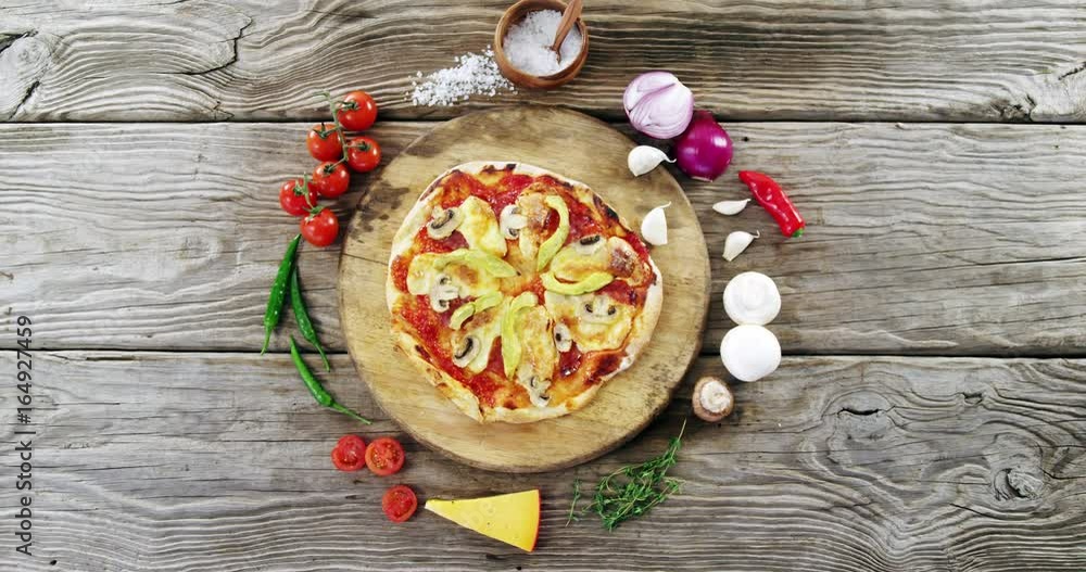 Italian pizza on wooden table with vegetables and spices Italian pizza on wooden table with vegetables and spices