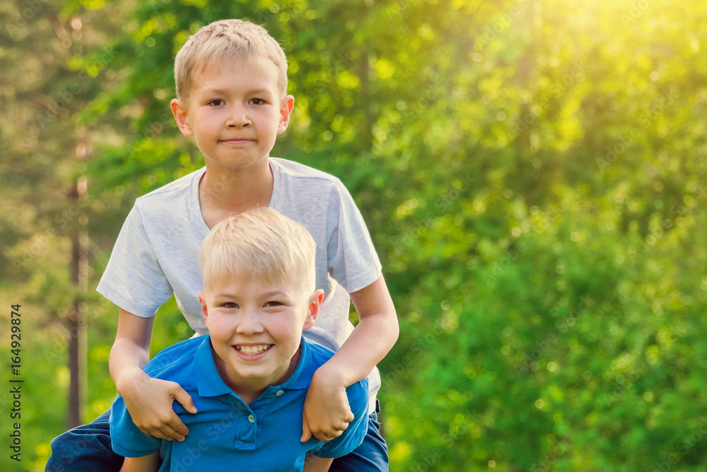Fototapeta premium Boy sitting on the back of a friend in the sunshine