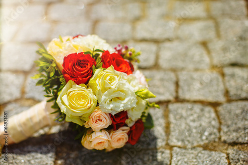 A wedding bouquet of roses, lying on a stone old sidewalk