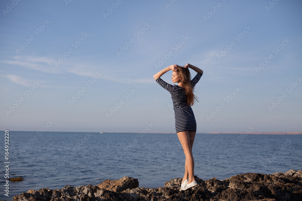 girl on the rocky beach looks at sea