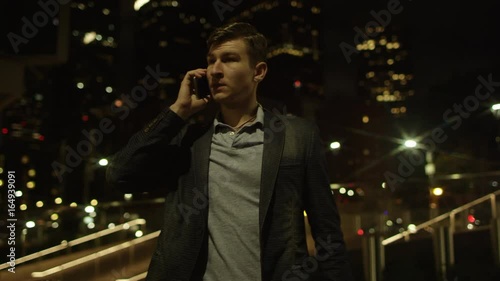 Happy young man is calling someone over his smartphone on a street photo