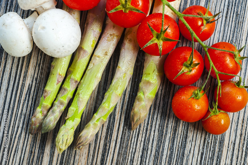 cherry tomatoes, asparagus and mushrooms on a wooden background