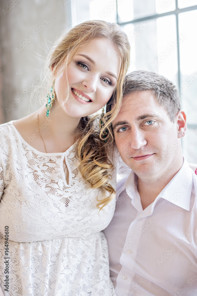 Naklejka premium A loving beautiful couple hugging and kissing by the window