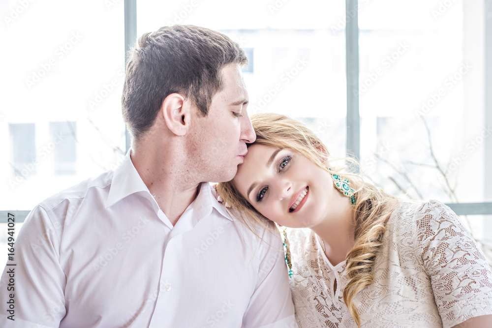 A loving beautiful couple hugging and kissing by the window A loving beautiful couple hugging and kissing by the window