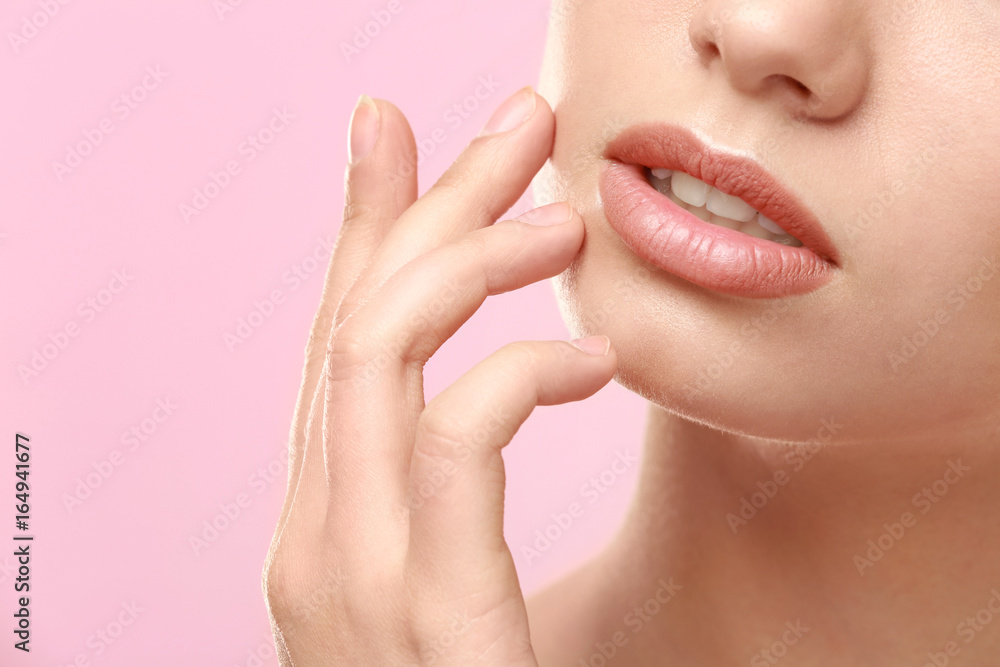 Closeup view of beautiful young woman with natural lips makeup touching face on color background Closeup view of beautiful young woman with natural lips makeup touching face on color background