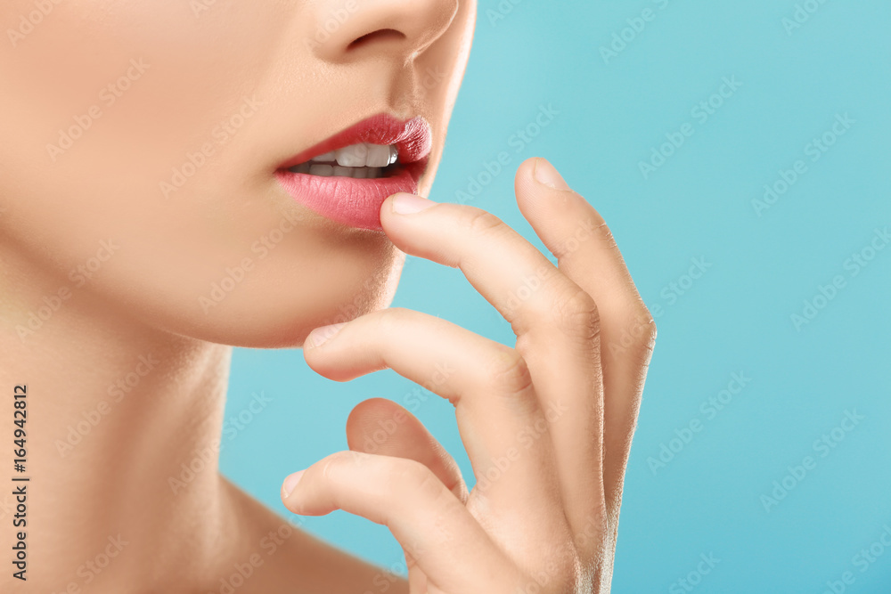 Closeup view of beautiful young woman with natural makeup touching lips on color background Closeup view of beautiful young woman with natural makeup touching lips on color background