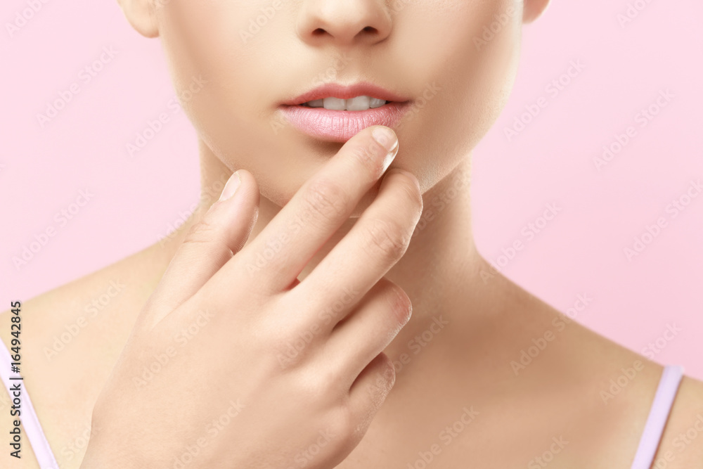 Closeup view of beautiful young woman with natural makeup touching lips on color background Closeup view of beautiful young woman with natural makeup touching lips on color background