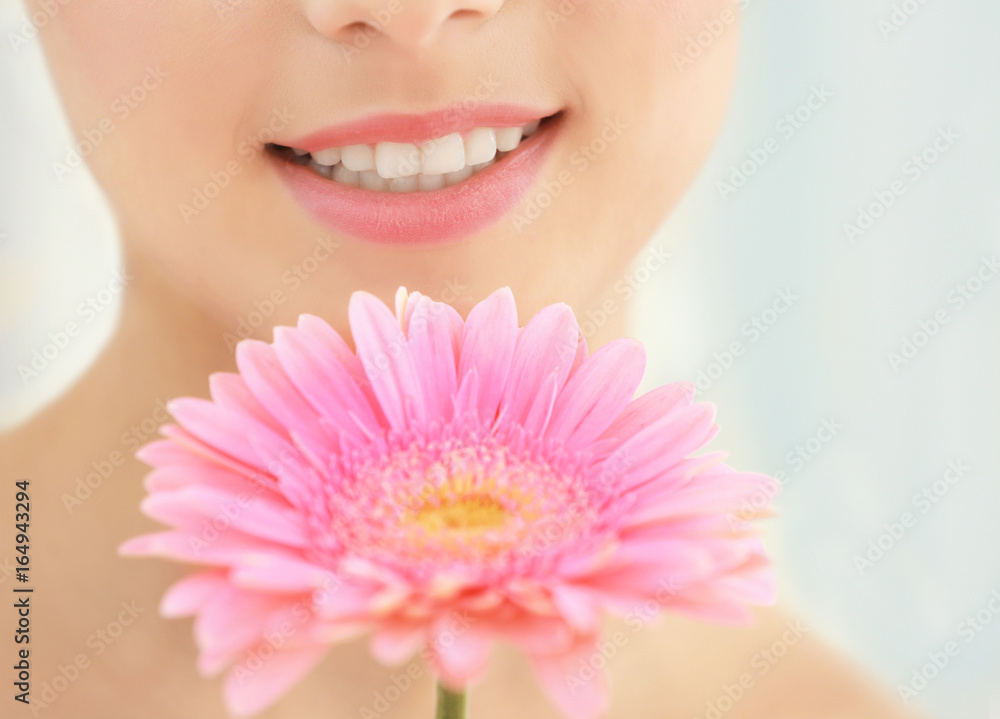 Woman with natural makeup and flower near face on blurred background Woman with natural makeup and flower near face on blurred background