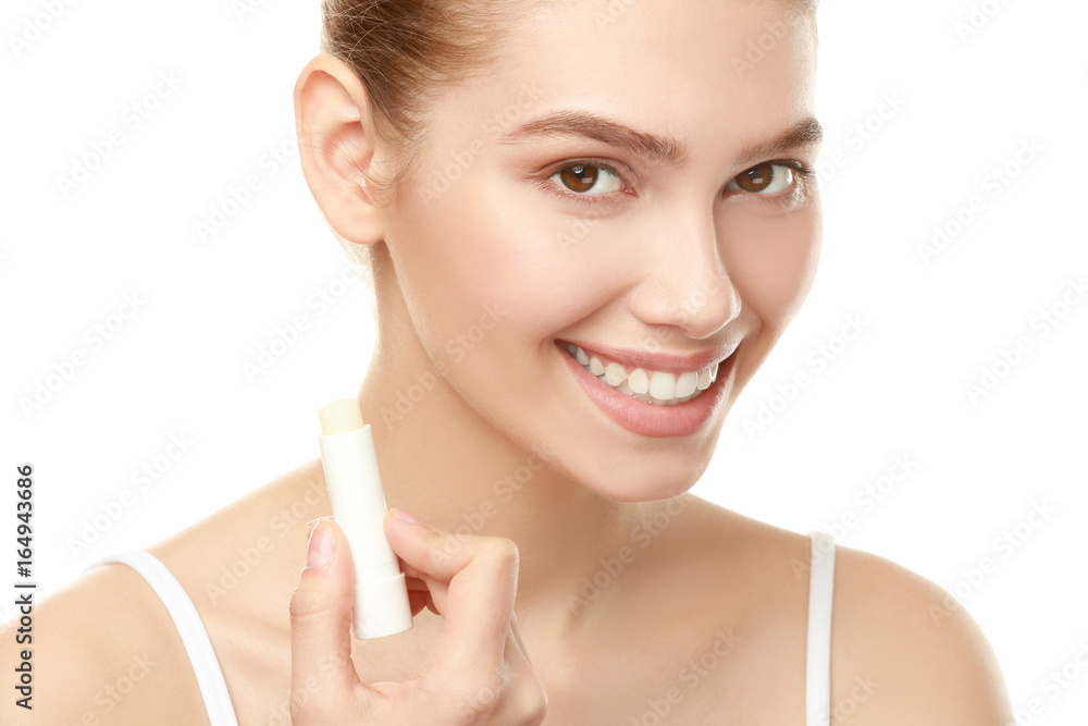 Smiling girl holding lipstick near face on white background Smiling girl holding lipstick near face on white background