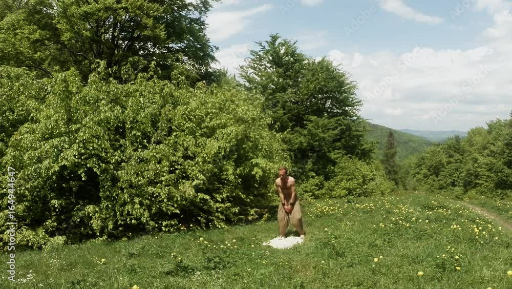 Yogi Doing Physical Exercise in Yellow Flowers in the Forest on Green Grass in the Mountains in Summer Overall Plan Yogi Doing Physical Exercise in Yellow Flowers in the Forest on Green Grass in the Mountains in Summer Overall Plan