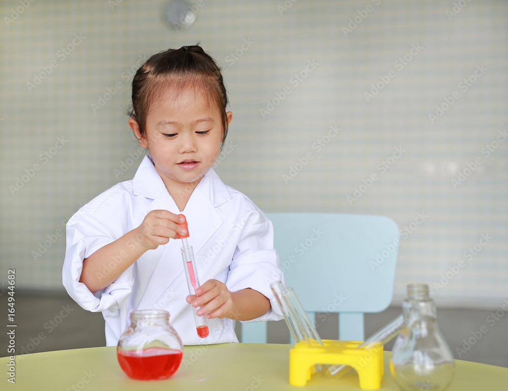 Asian child in scientist uniform holding test tube with liquid, Scientist chemistry and science education concept. Asian child in scientist uniform holding test tube with liquid, Scientist chemistry and science education concept.