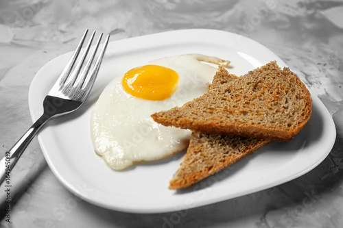 Delicious over easy egg with bread slices on table