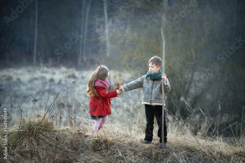 ittle boy and girl stand in a field in early spring