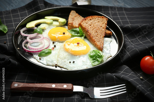 Delicious over easy eggs with toasts, onion and avocado on kitchen table