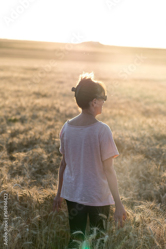 Woman in a wheat field at sunset, sunlight effect