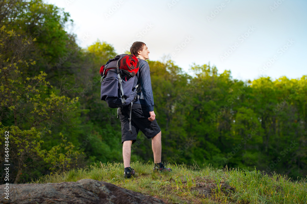 Young guy standing on top of the mountain, enjoying the view. Beautiful forest background Young guy standing on top of the mountain, enjoying the view. Beautiful forest background