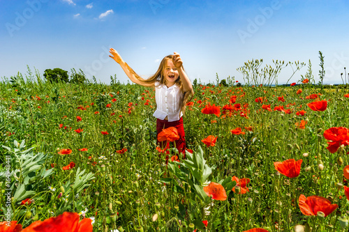 Fototapeta Naklejka Na Ścianę i Meble -  Cute little girl playing in red poppies field summer day, beauty and happiness