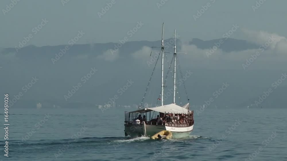 Tour boat with tourists sailing away from Ilhabela, Brazil Tour boat with tourists sailing away from Ilhabela, Brazil