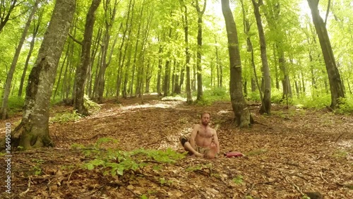 Bare-Waisted Man Doing Yoga in Sedentary Poses in the Old High Green Sunny Forest Overall Plan