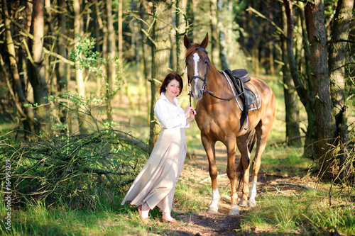 woman walks with the favourite horse in the wood
