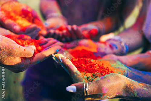 close-up partial view of young people holding colorful paint in palms at holi festival
