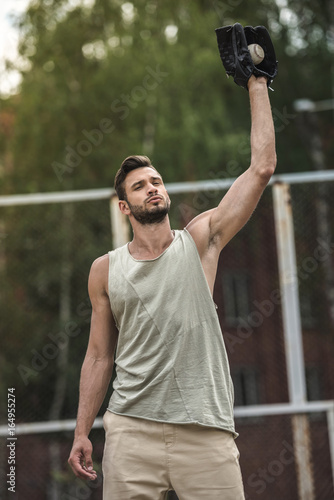 young handsome man catching baseball ball on court