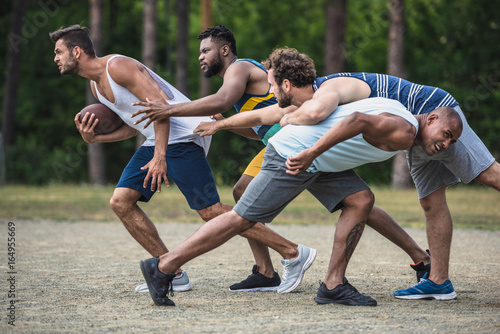 group of young multicultural men playing football on court © LIGHTFIELD STUDIOS