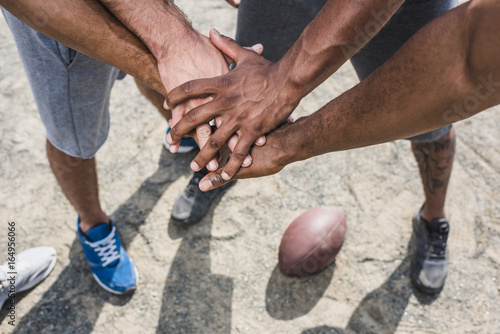 group of young multicultural men holding hands before football game