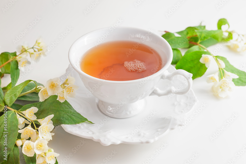 Cup of tea with jasmine flowers on a white table Cup of tea with jasmine flowers on a white table