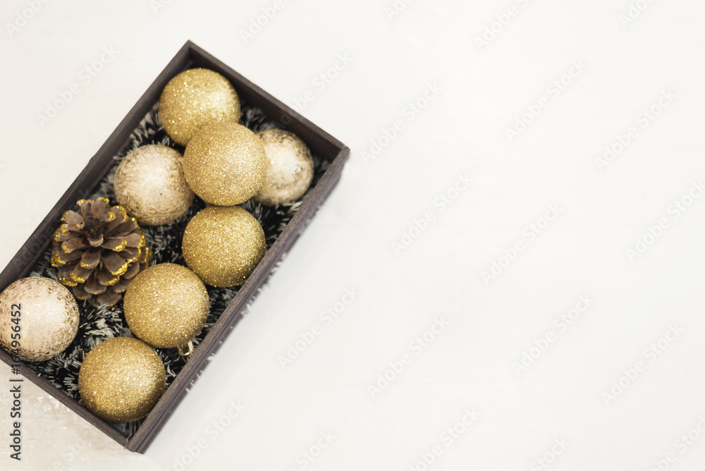 Golden Christmas balls in a wooden crate on a white rustic wooden background. Top view Golden Christmas balls in a wooden crate on a white rustic wooden background. Top view