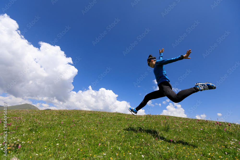 joyfully woman running jumping on mountain grassland