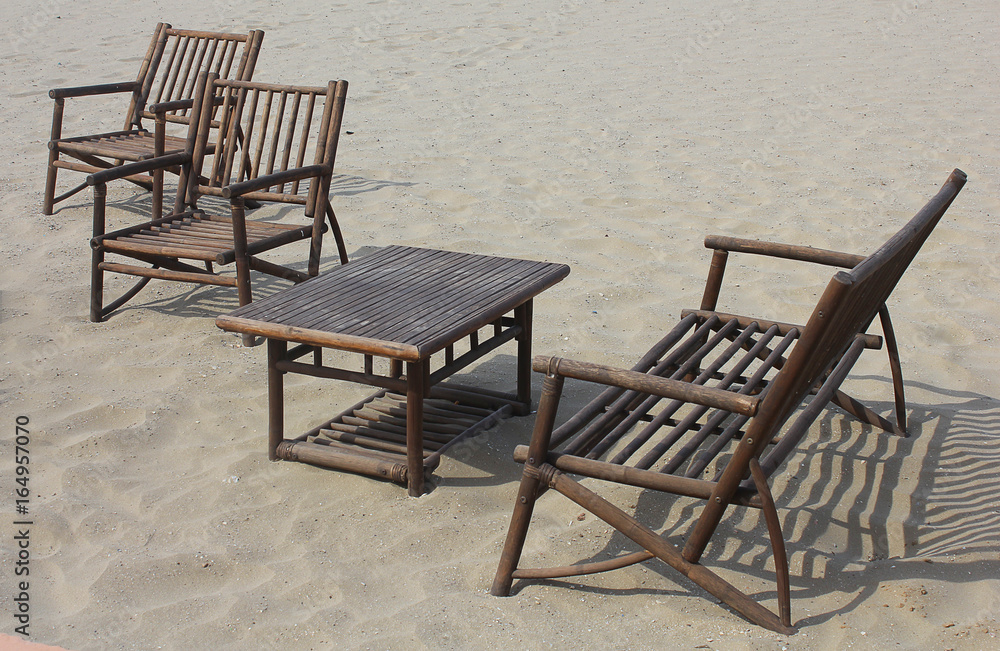 chairs and table made with wood on the sand