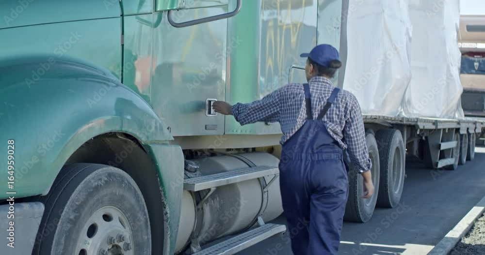 Tilt up slow motion of African delivery woman getting into driver cabin of large truck Tilt up slow motion of African delivery woman getting into driver cabin of large truck
