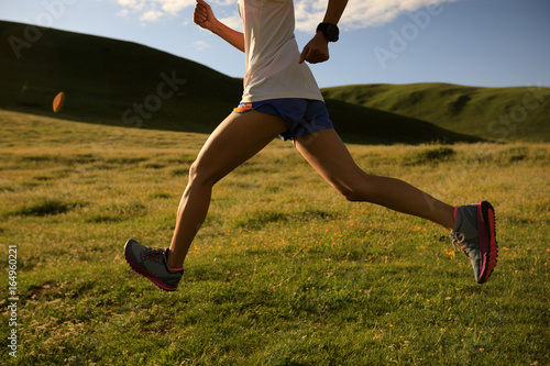 young fitness woman runner running on sunset grassland trail