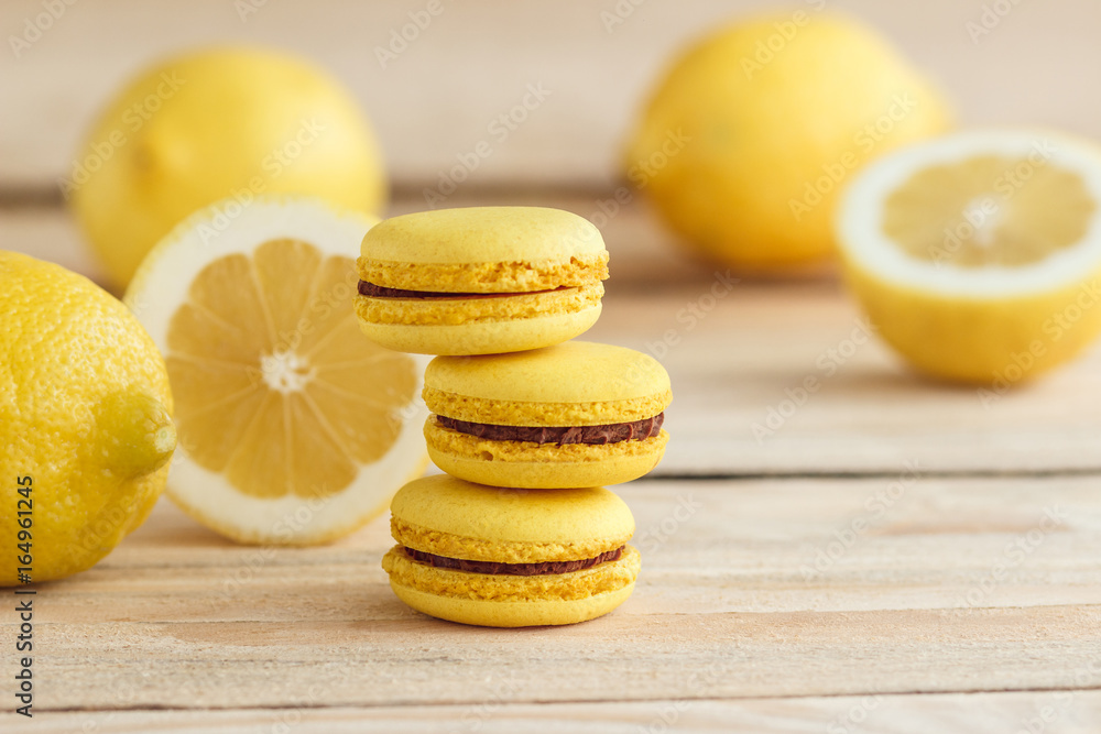Yellow french macarons with lemons on the wooden board Yellow french macarons with lemons on the wooden board
